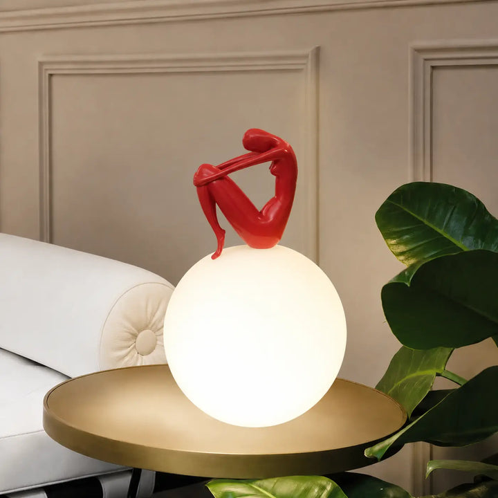 Lampe de table kelya avec silhouette enlacée rouge perchée sur base lumineuse sphérique blanche en design contemporain