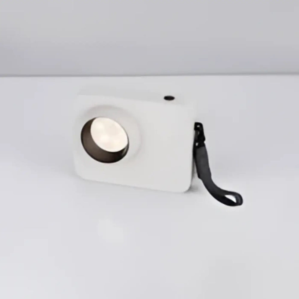 Lampe de table focalis en plastique blanc avec faisceau lumineux ciblé et sangle noire autour de lobjectif circulaire
