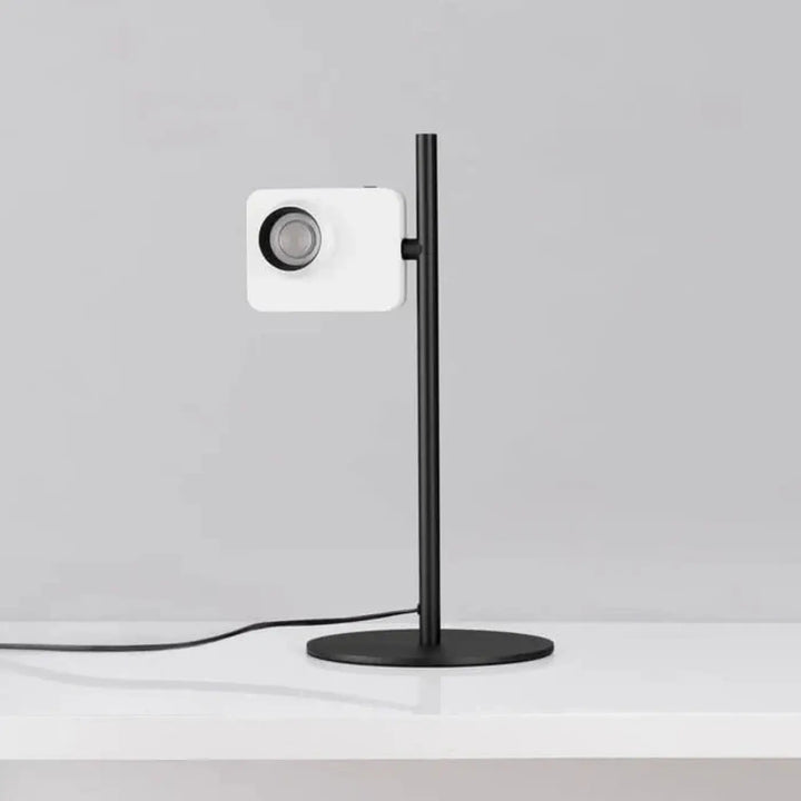 Lampe de table eclia avec éclairage directionnel blanc et tige élancée sur un stand noir design pour table
