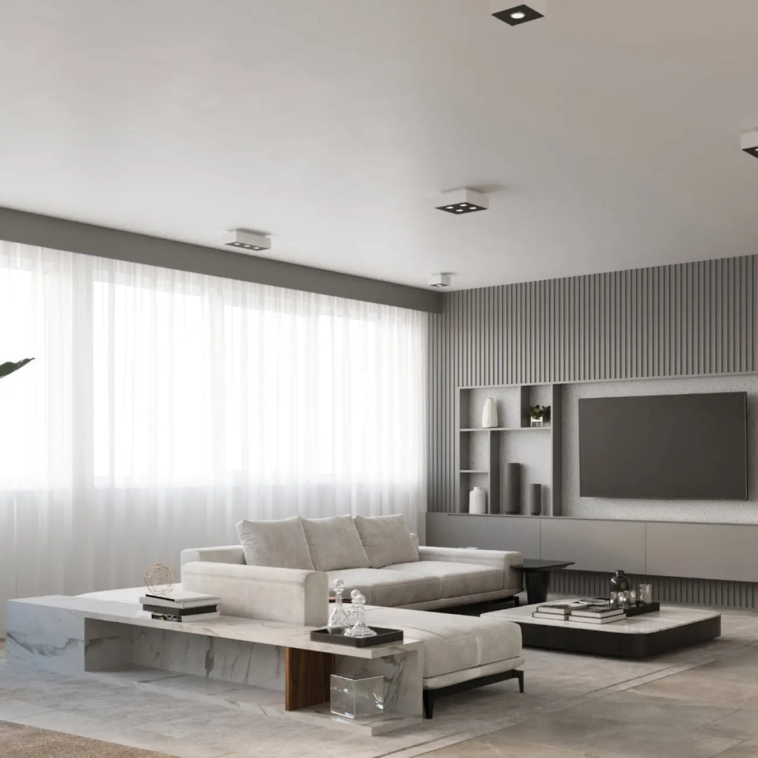 Luminaire plafonnier mono 3 blanc dans un salon moderne avec canapé blanc, tables en marbre, murs gris, spot allongé plafonnier moderne sources lumineuses