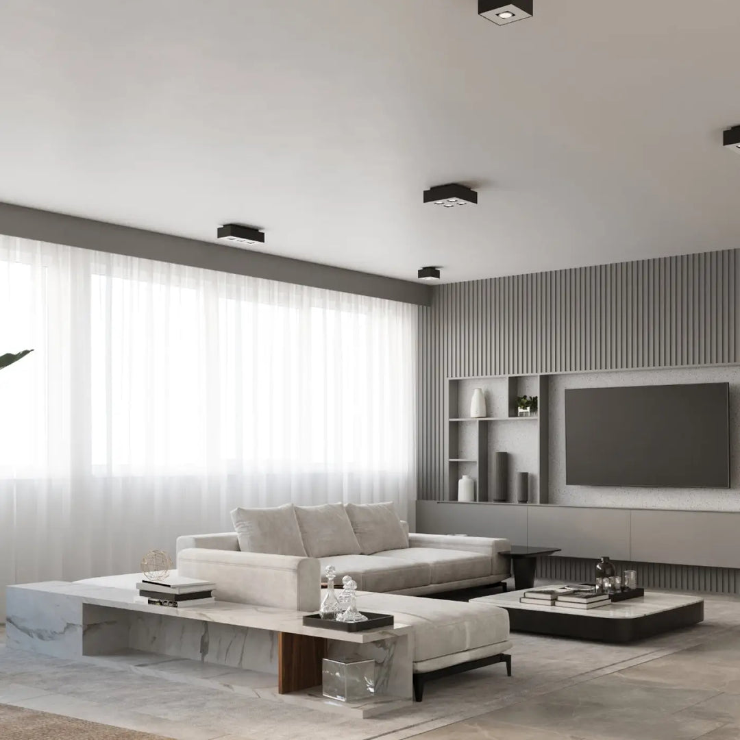 Luminaire plafonnier mono 1 noir dans un salon moderne avec un canapé blanc et des spots allongés encastrés au plafond