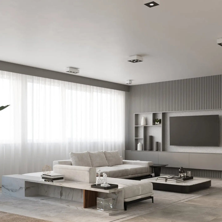 Luminaire plafonnier moderne mono blanc dans un salon minimaliste avec canapé blanc et tables en marbre