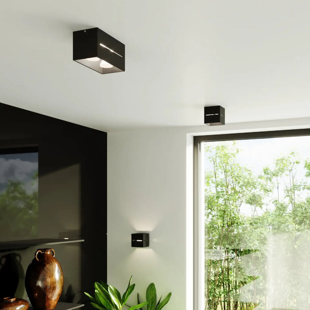 Plafonnier lobo 2 noir avec perforation linéaire diffusant un spectacle lumineux moderne sur plafond et murs
