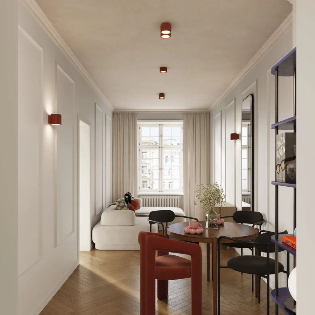 Luminaire plafonnier aura 1 rouge ochra au-dessus dune table ronde en bois avec chaises noires et une rouge forme unique inspirée