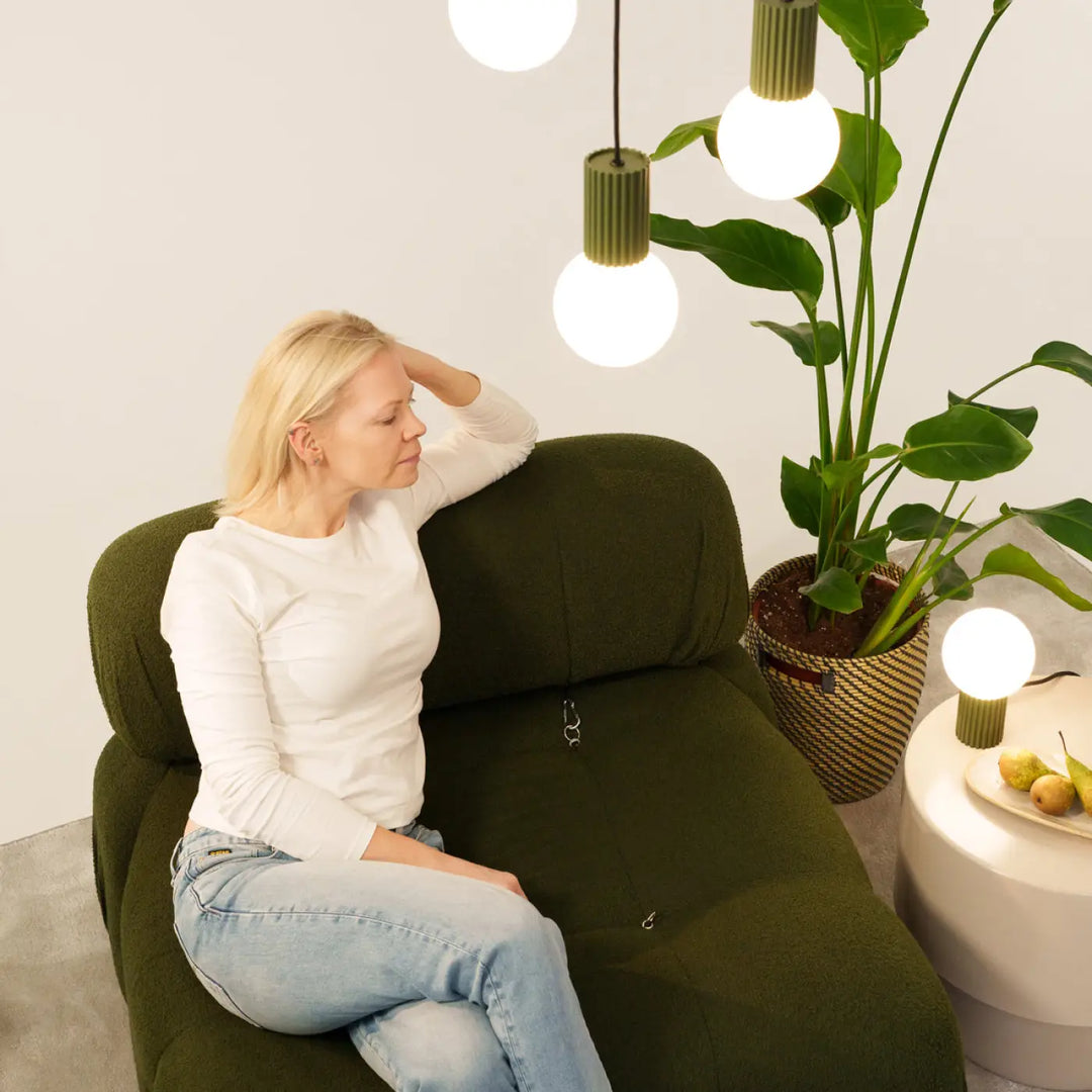 Fauteuil vert olive en tissu avec coussin moelleux et couture visible associé à lampe halo sphère laiteuse bureau décorative