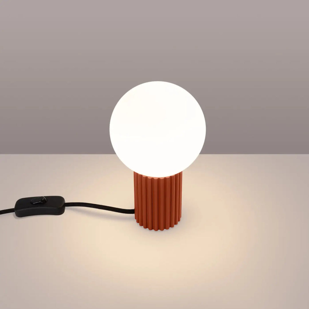 Lampe à poser ocre rouge allumée