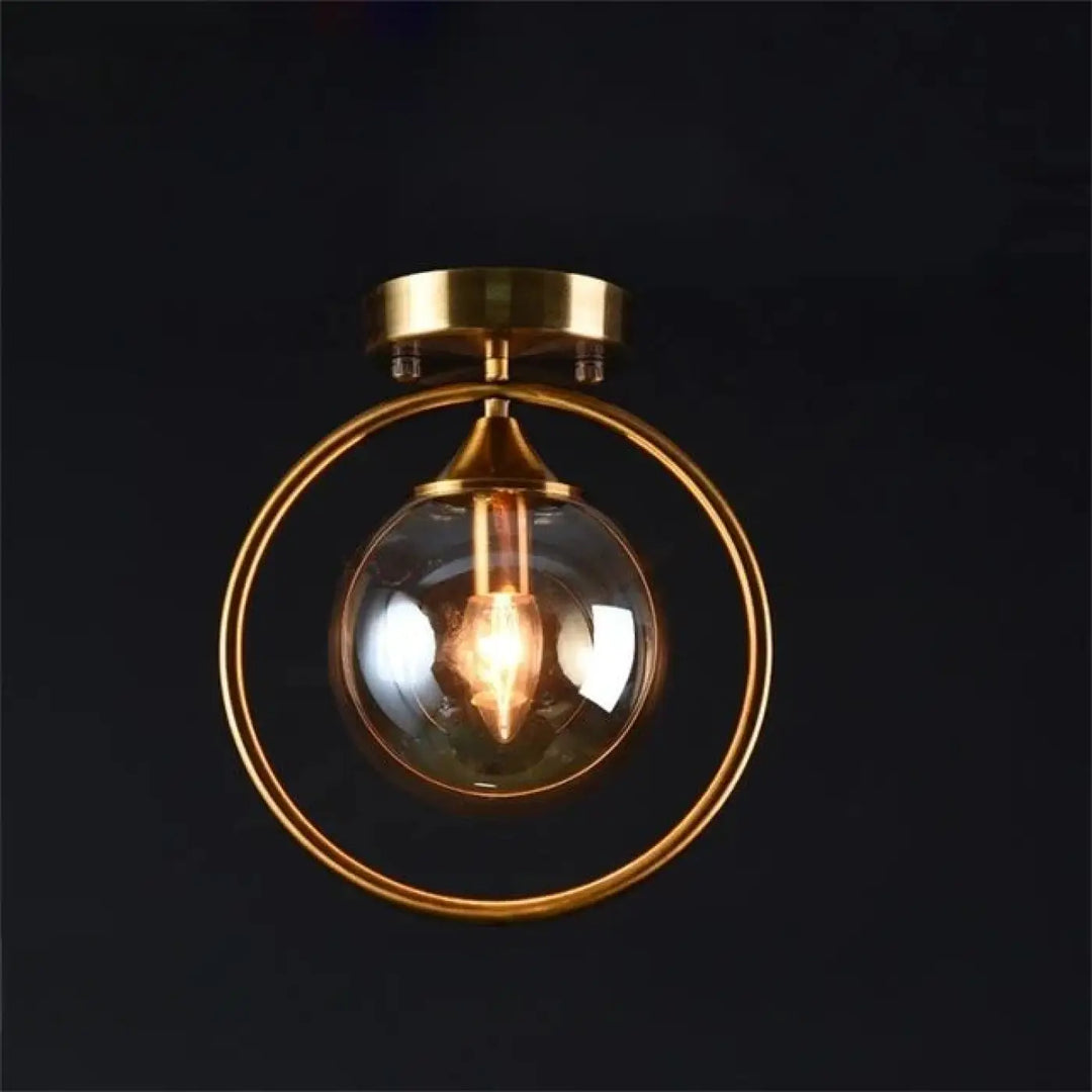 Plafonnier chic orbane en anneau doré avec boule lumineuse en verre clair et ampoule à filament visible