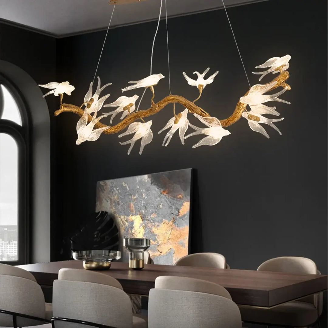 Luminaire plafonnier winglow avec branche dorée et luminaires blancs translucides en forme d’oiseaux