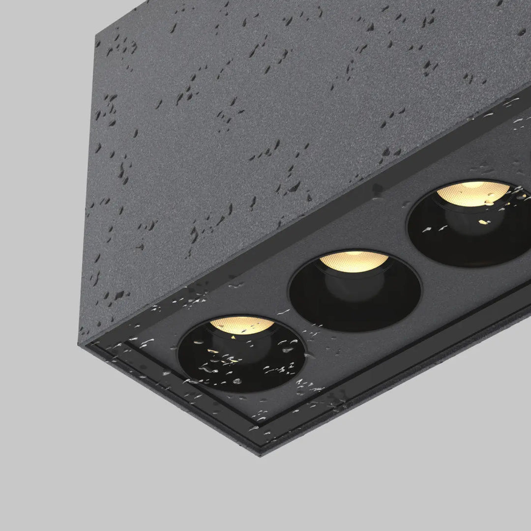 Plafonnier extérieur ares en métal graphite noir avec trois ampoules led chaudes encastré long dune galerie sur surface grise texturée