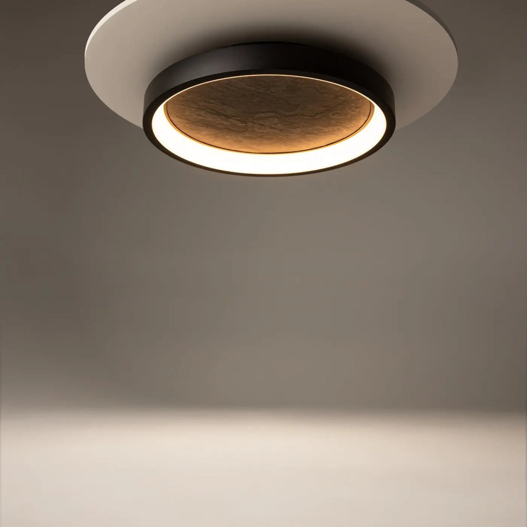 Luminaire plafonnier orign effet pierre avec cadre noir mat anneau blanc et lumière chaude diffuse au centre texturé