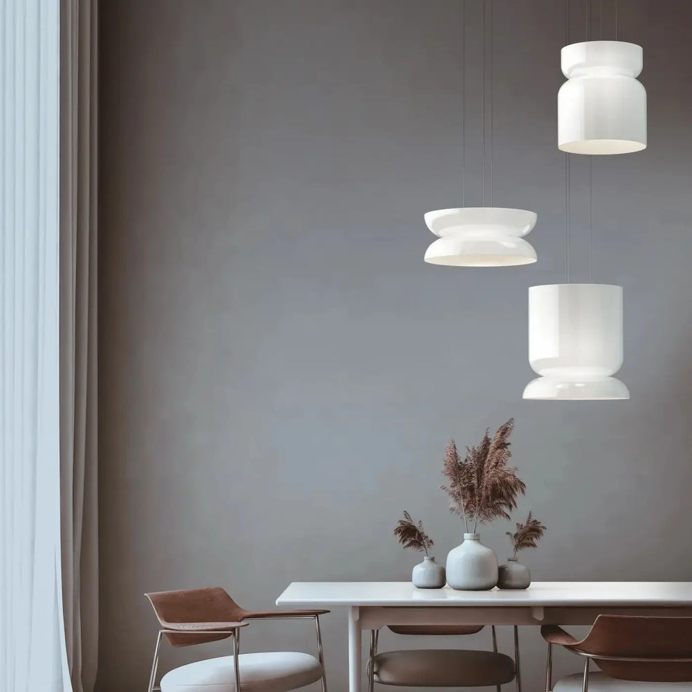 Trois luminaires plafonniers totem en verre opale soufflé blancs suspendus à différentes hauteurs au-dessus d une table à manger par pablo designs