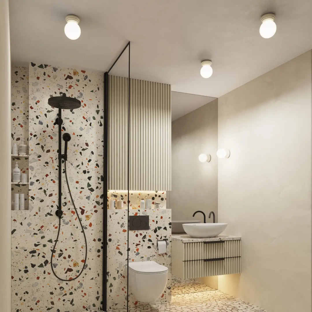 Douchette noire avec flexible et fixations assorties contre un mur terrazzo blanc pour lampe zori et belle décoration