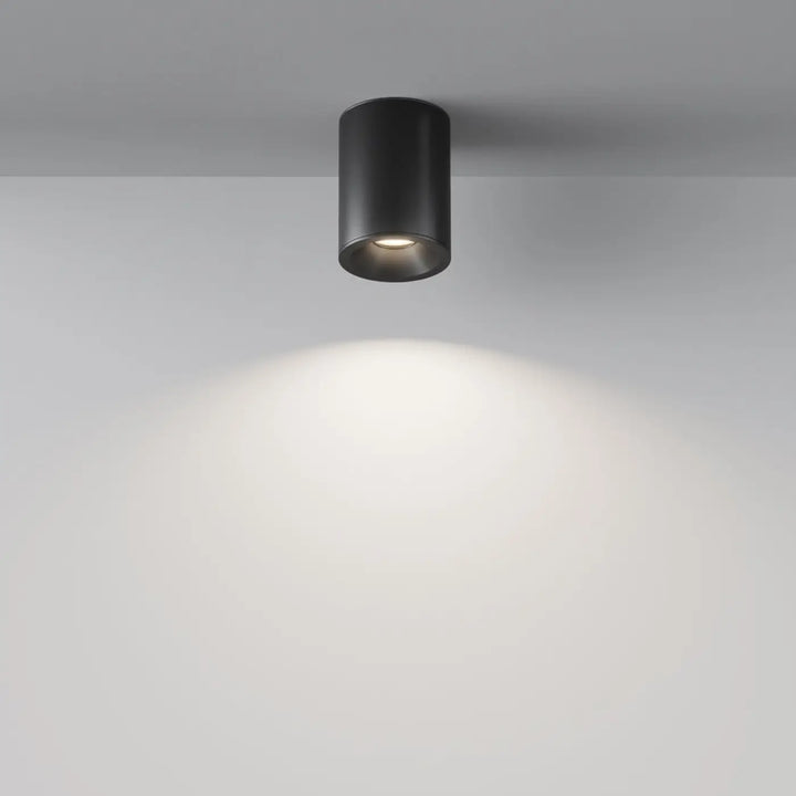 Spot zoom cylindre noir mat encastré au faux plafond avec lumière dirigée chaude et focalisée