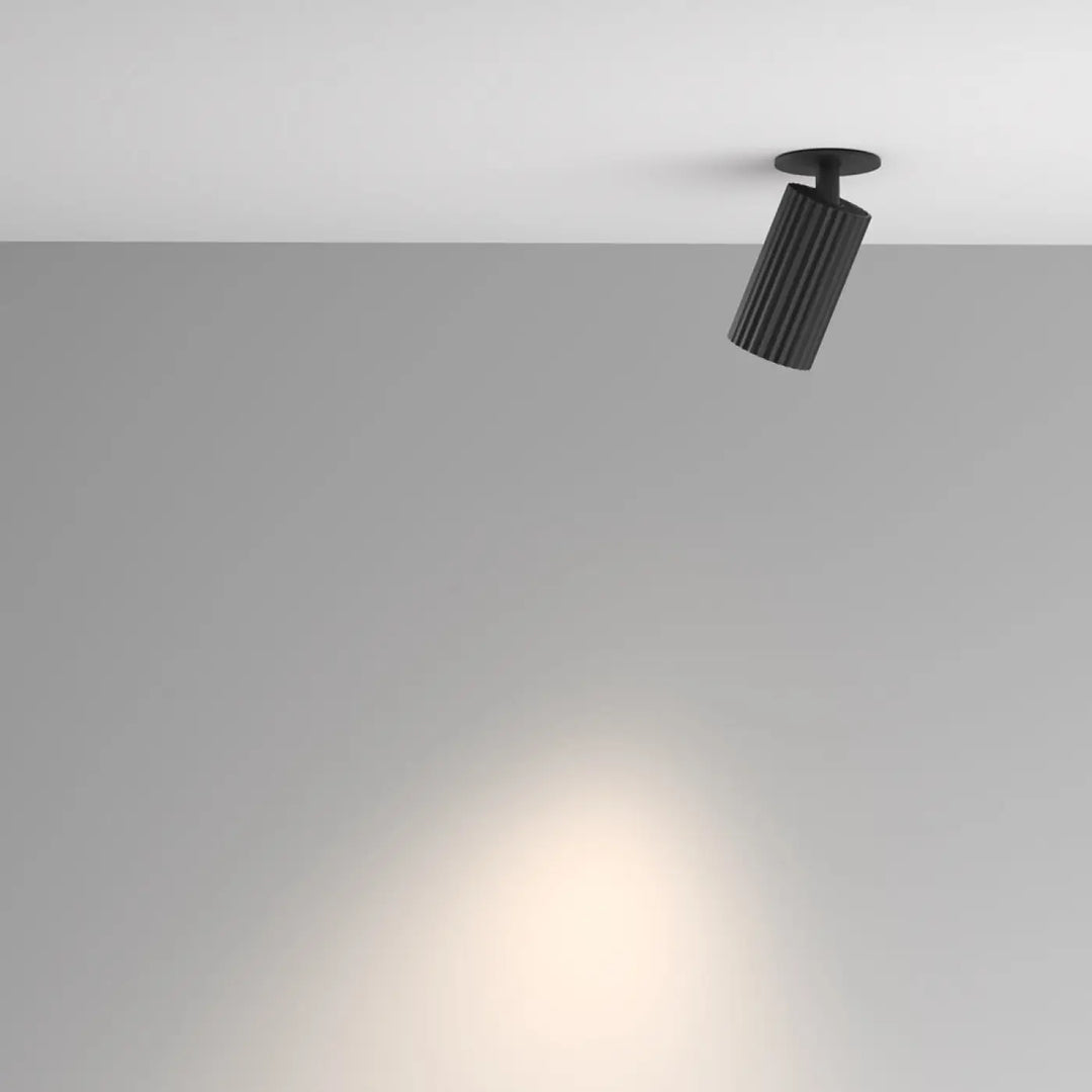 Spot semi-encastré calipso cylindre cannelé noir avec finition mate émettant une lumière chaude et focalisée