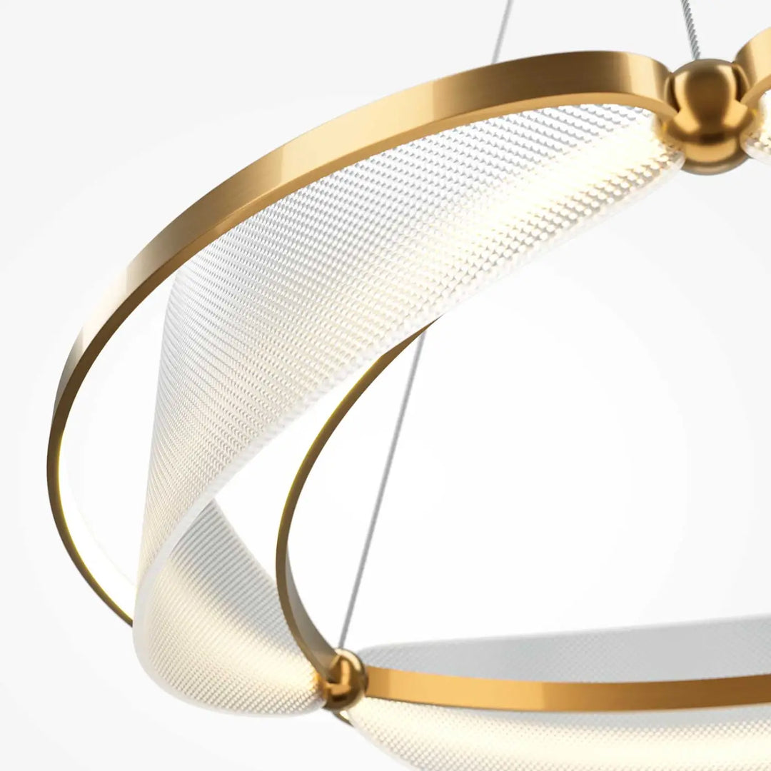 Suspension luminaire breeze anneau avec panneaux en acrylique texturé blanc et anneaux métalliques dorés au-dessus d’une table