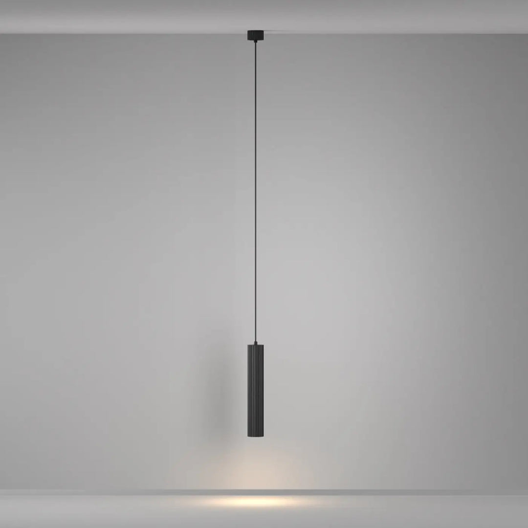 Suspension luminaire calipso tube noire cylindrique avec rainures verticales au-dessus d’un îlot pour un éclairage minimaliste