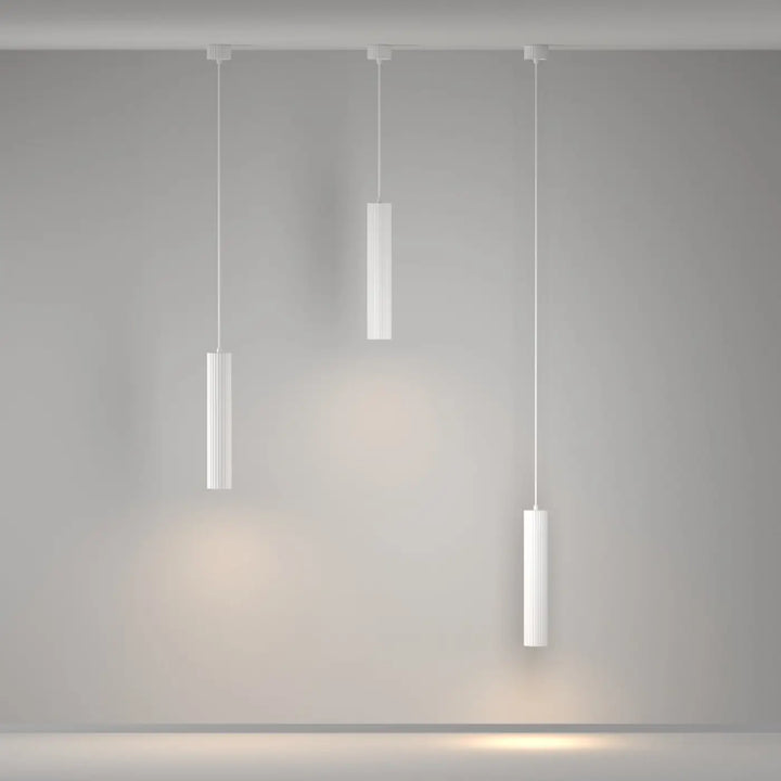 Suspension luminaire calipso tube avec trois lampes cylindriques blanches et rainurées au-dessus d’un îlot