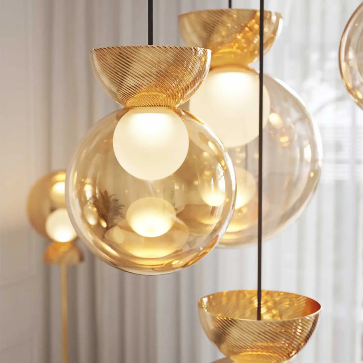 Suspension charm sphère avec globe lumineux en verre sablé doré suspendu par cordons noirs à coupelles métalliques texturées