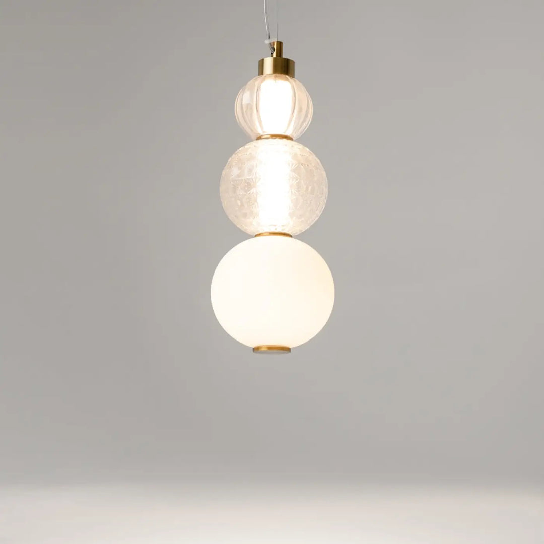Suspension collar en métal doré avec trois globes en verre texturés offrant une lumière à 360°