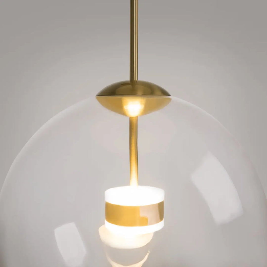 Suspension cometa avec verre soufflé en globe transparent et bande dorée, idéale au-dessus d’une table moderne