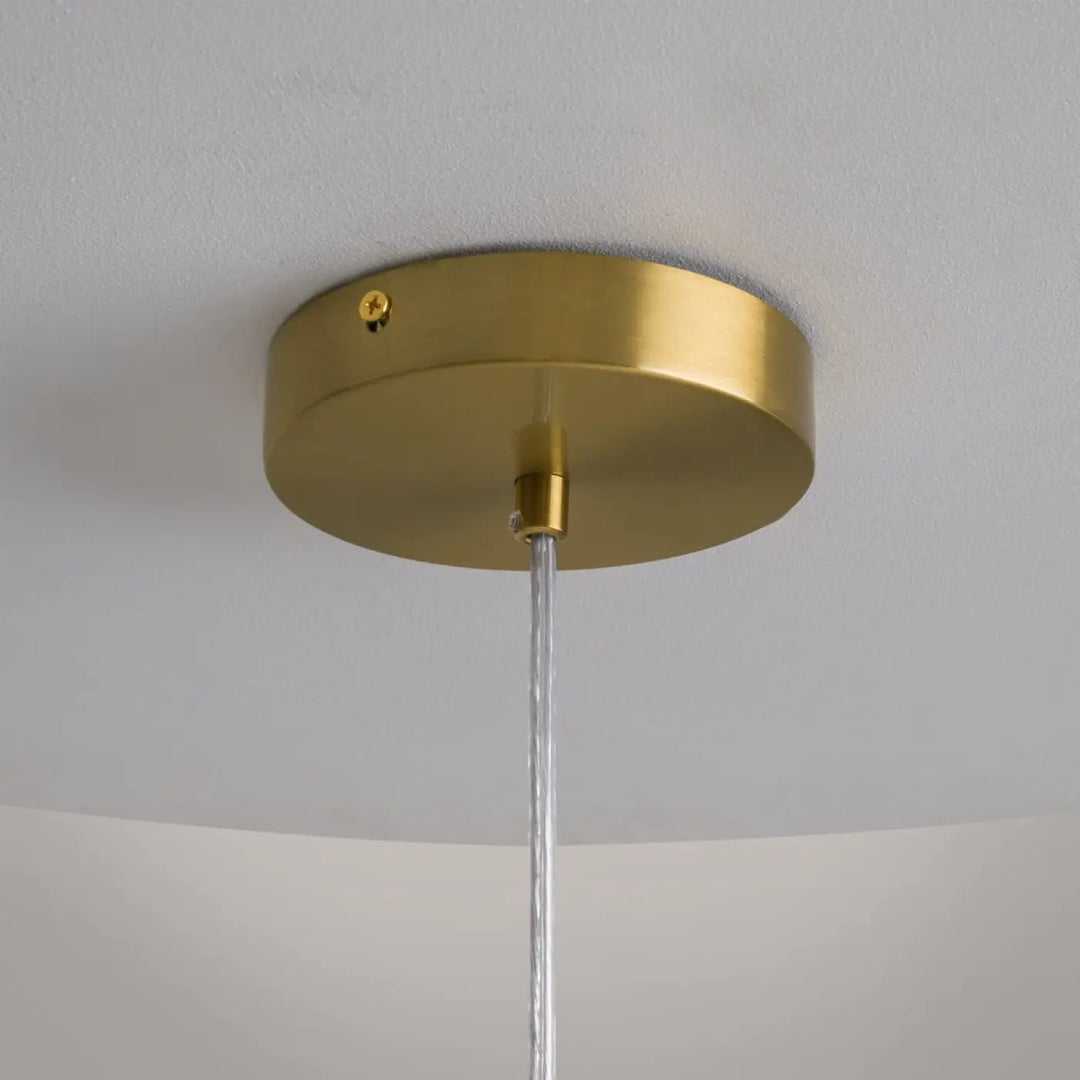 Luminaire suspension cometa en laiton finition circulaire avec câble transparent verre soufflé au-dessus d’une table