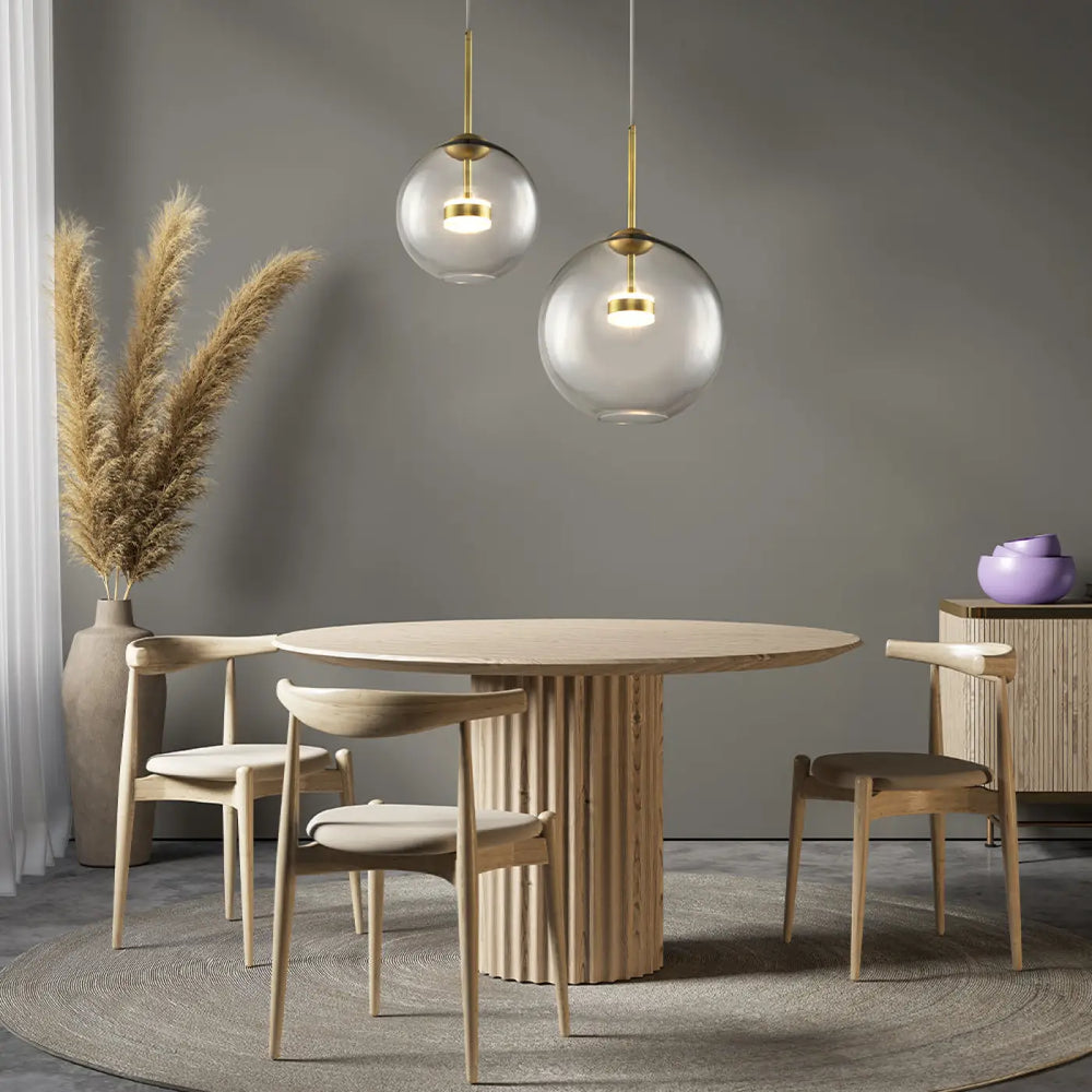 Suspension cometa en verre soufflé suspendue au-dessus dune table ronde moderne en bois clair à pied cannelé