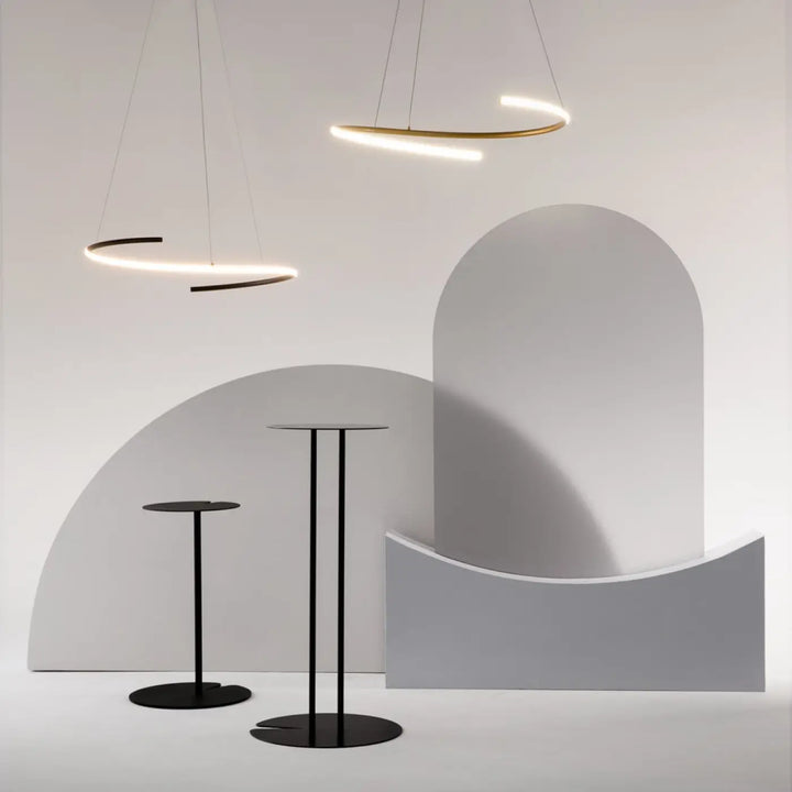 Minimalist black metal cocktail tables with sleek circular tops and slender legs complement aluminium noir suspension curve anneau ondulé design