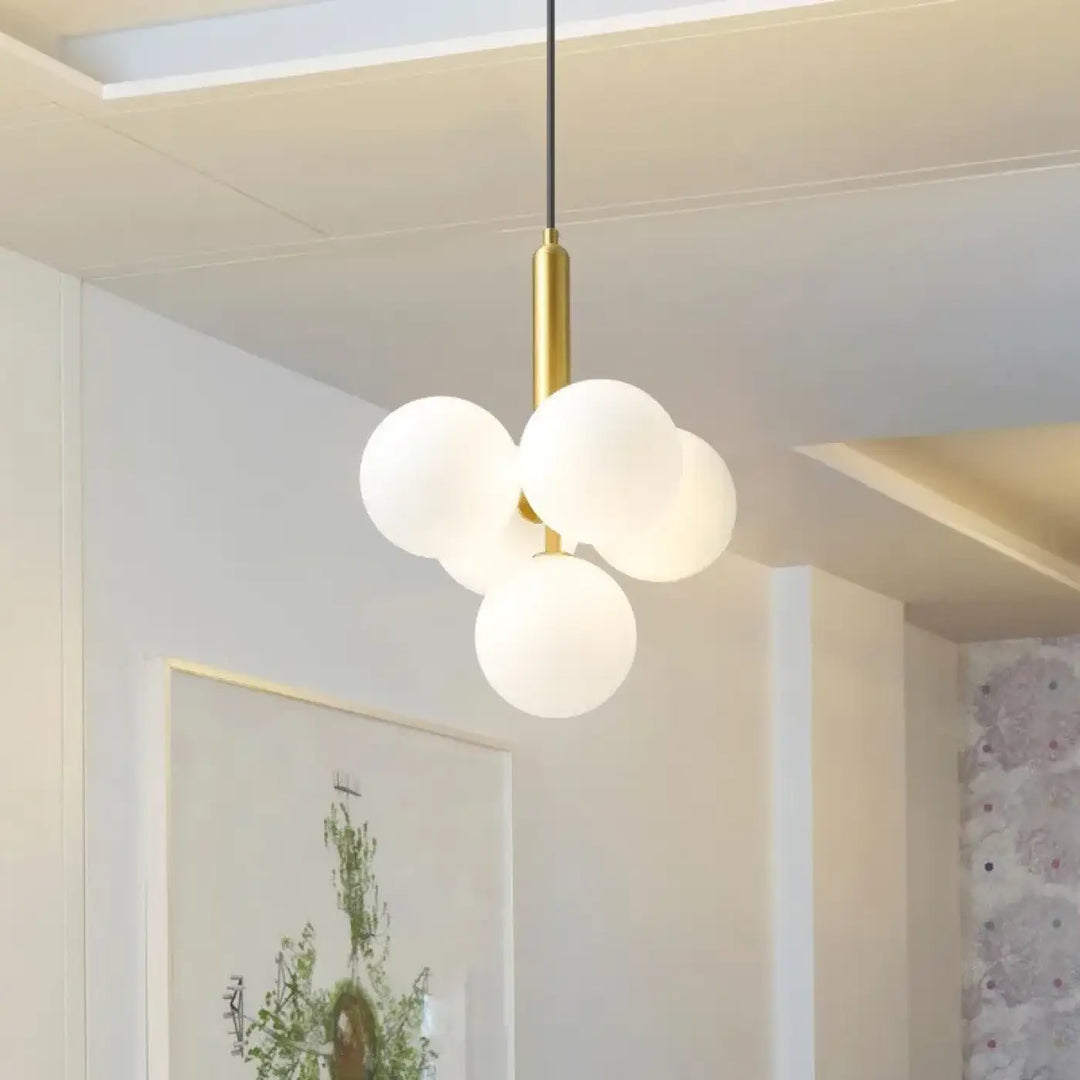 Suspension luminaire dinah avec tige métallique finition or et quatre globes ronds en verre blanc laiteux moderne