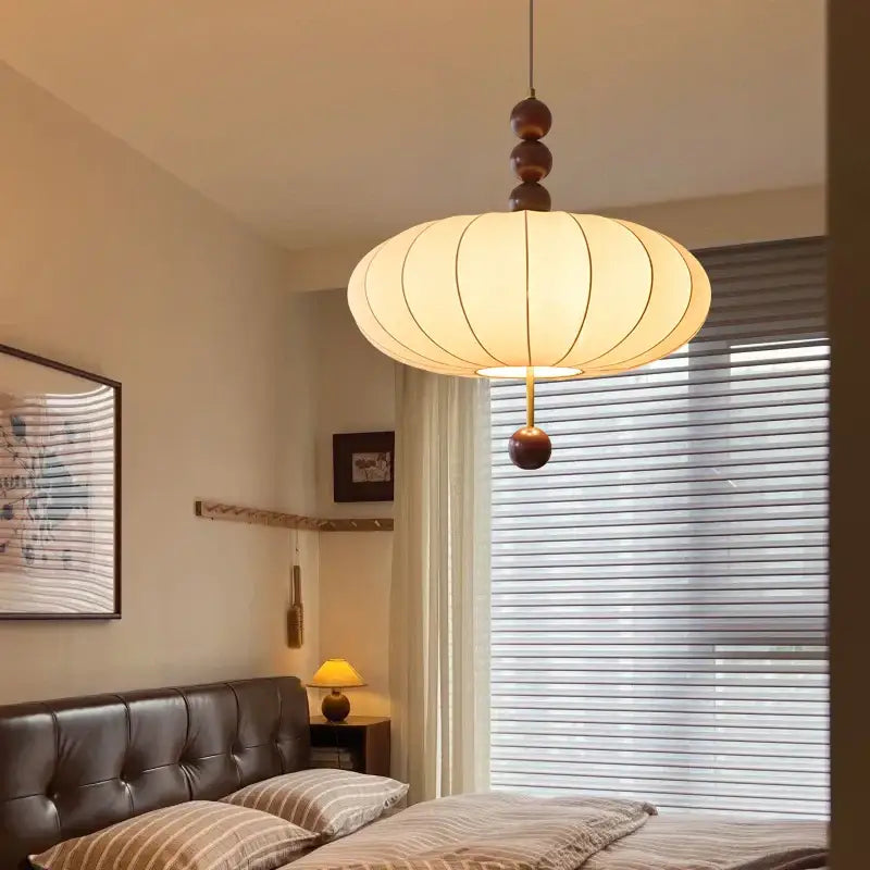 Suspension design en tissu beige et boules de bois modernes

