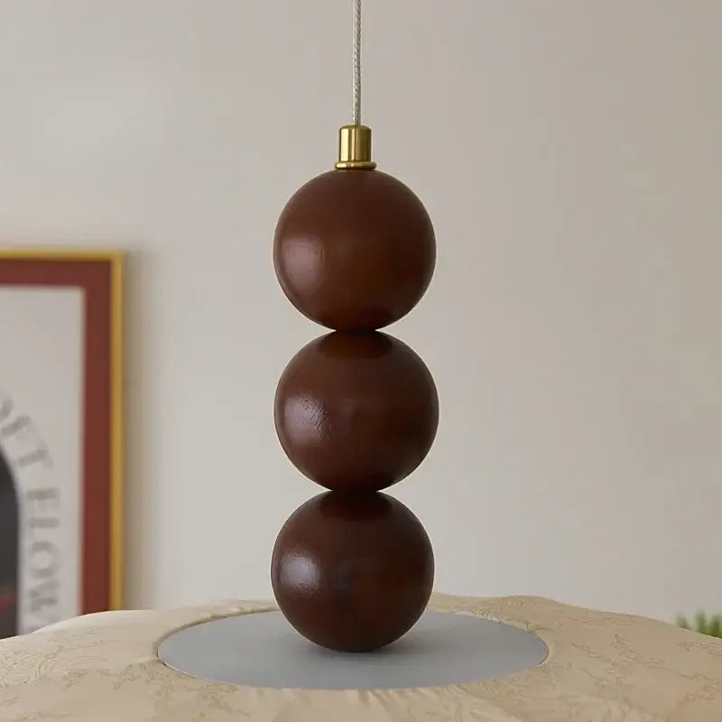 Suspension design en tissu beige et boules de bois modernes

