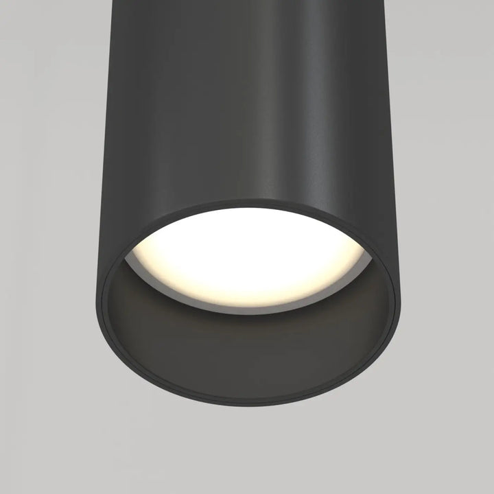 Suspension focus cylindre en métal noir mat avec tube fin et lumière chaude diffusée au-dessus d’un îlot