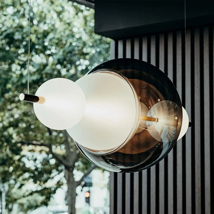 Suspension luminaire galileo avec abat-jour sphériques superposés en verre givré blanc et ambre sombre à fixations laiton