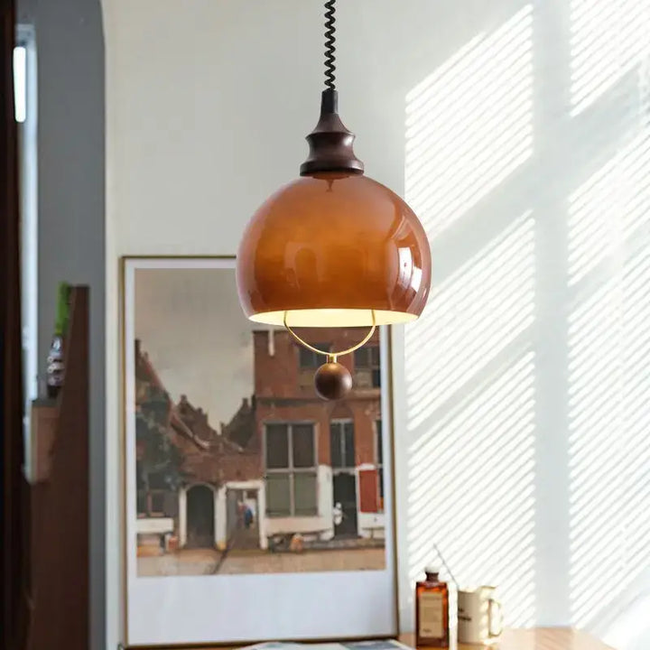 Suspension globe ambrée avec détail doré et boule décorative

