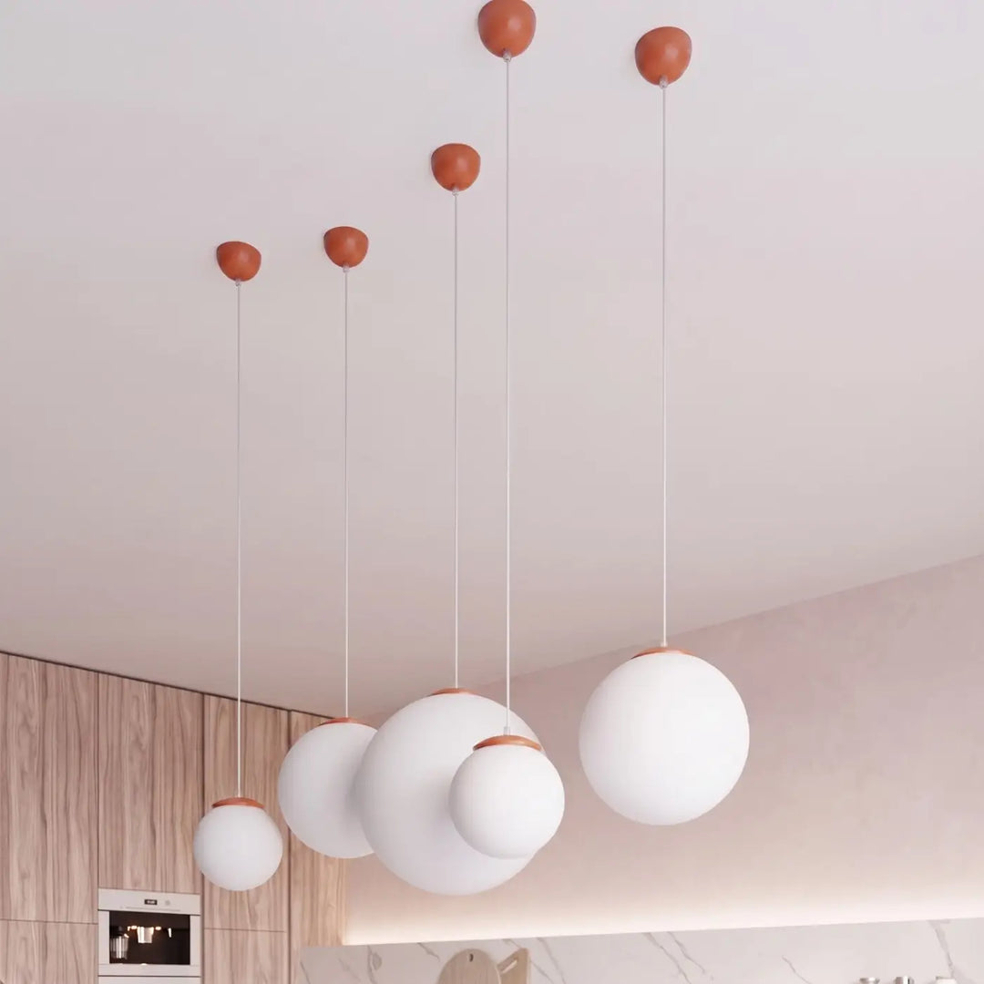 Suspension Ugo à globe en verre blanc et monture ocre rouge dans un intérieur contemporain