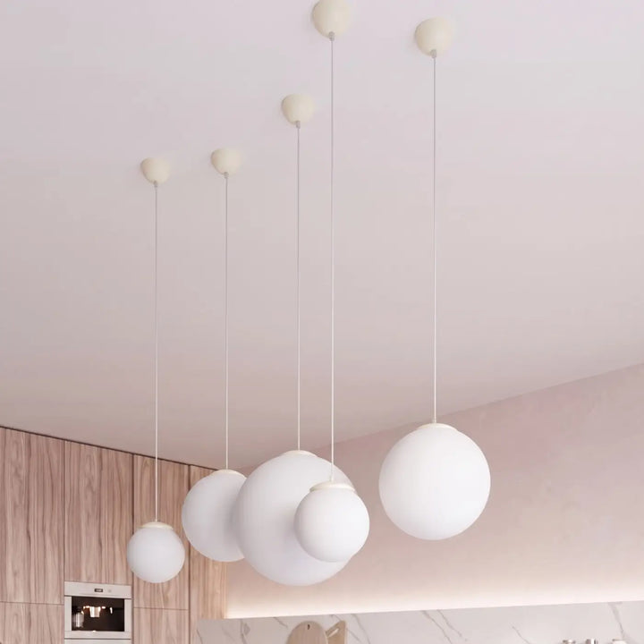 Suspension Ugo à globe en verre blanc et monture beige dans un intérieur contemporain
