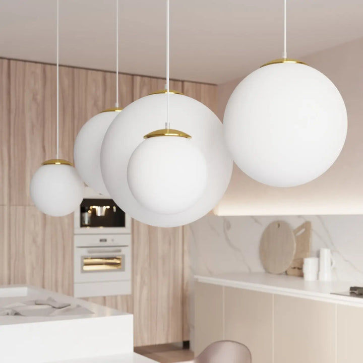 Suspension Ugo à globe en verre blanc et monture dorée dans un intérieur contemporain