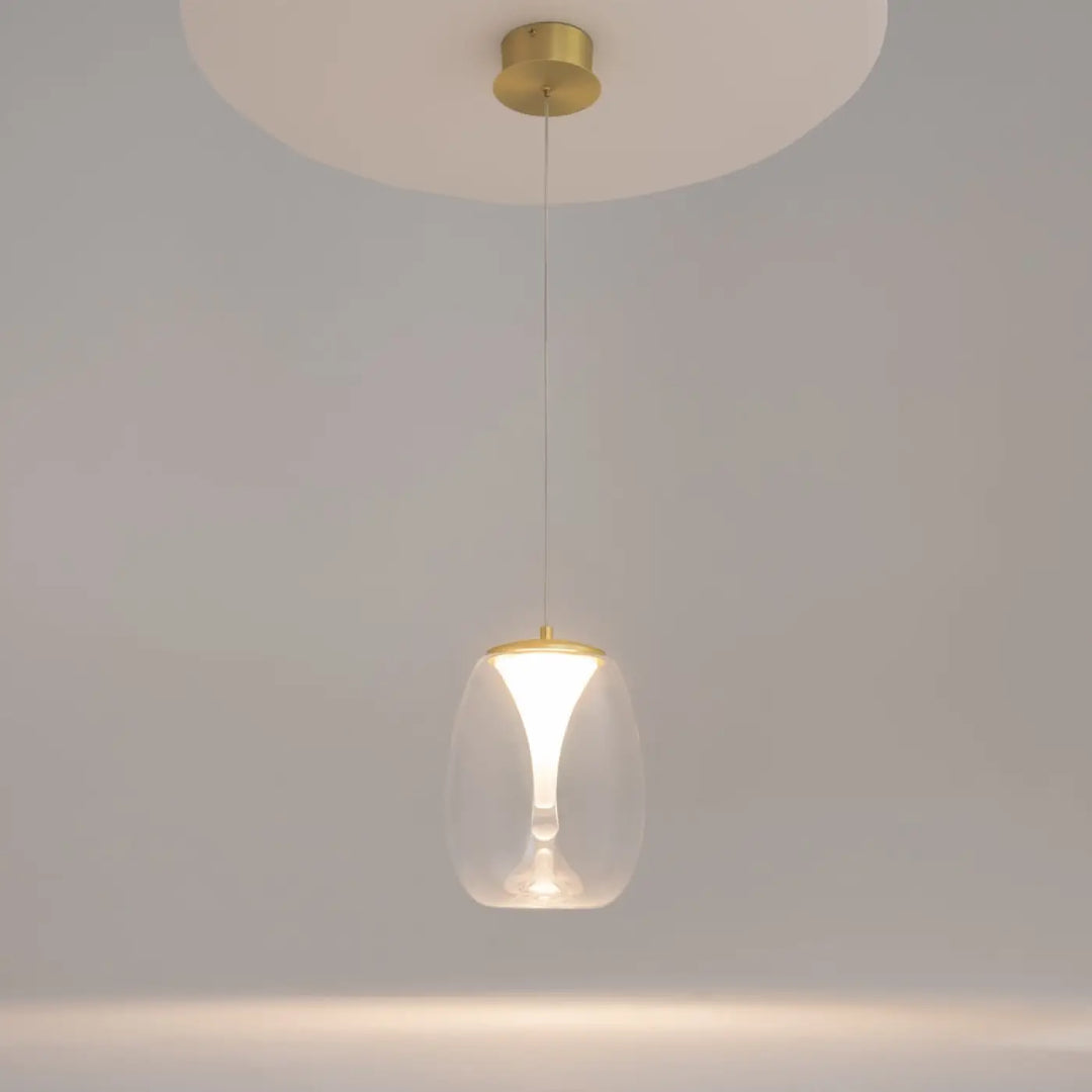 Suspension luminaire splash avec abat-jour en verre transparent et accents métal doré au-dessus d’un îlot cuisine