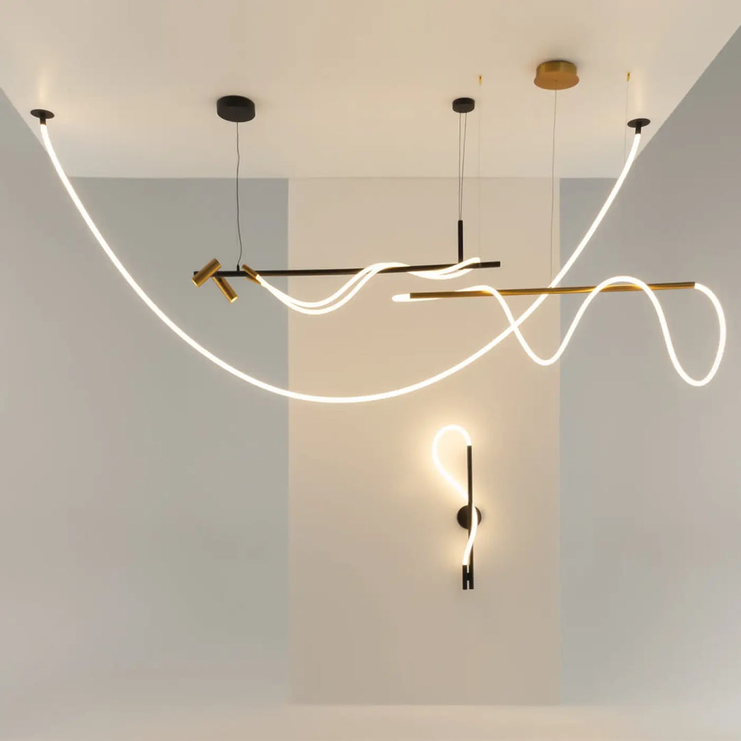 Suspension luminaire tau ruban noué en acier noir avec leds fluides au-dessus d’une structure metalique noire et or