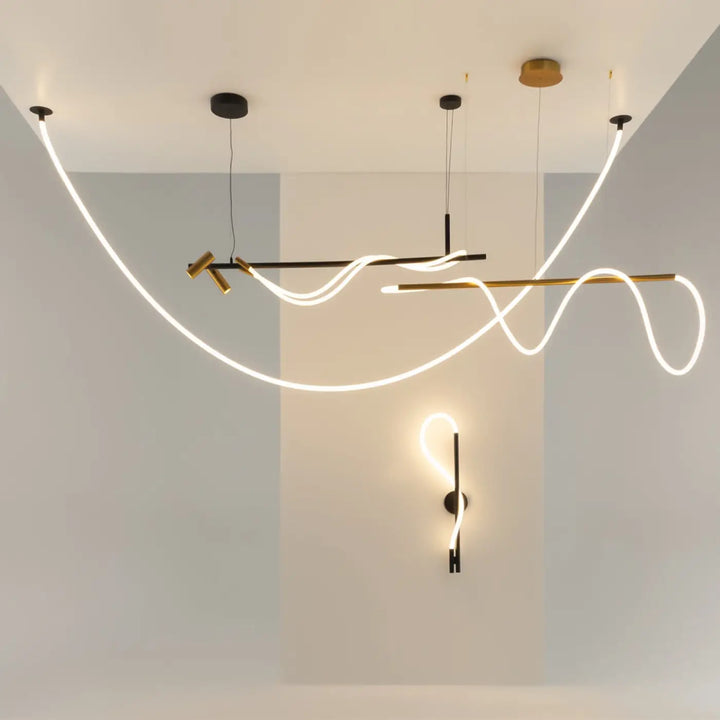 Suspension luminaire tau ruban noué en acier noir avec leds fluides au-dessus d’une structure metalique noire et or