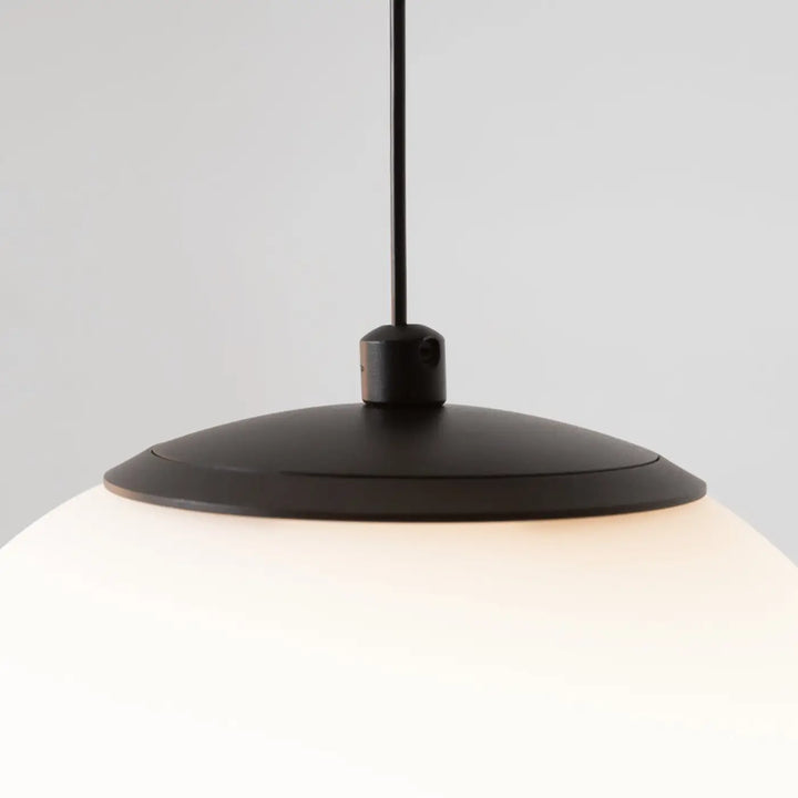 Suspension luminaire twins avec trois globes led en verre dépoli au-dessus d’une table finition mate noire