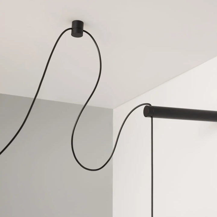 Suspension luminaire trois globes led noir mat au-dessus d’une table avec câble courbé minimaliste