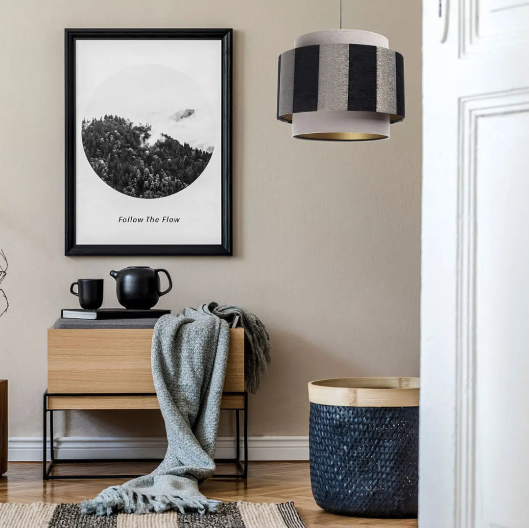 Suspension luminaire beige noir avec cadre noir et imprimé paysage noir et blanc suivi du texte follow the flow
