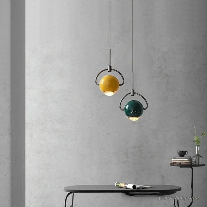 Suspension luminaire orion avec boules en verre sphériques jaune et bleu suspendues sur cadre métallique noir