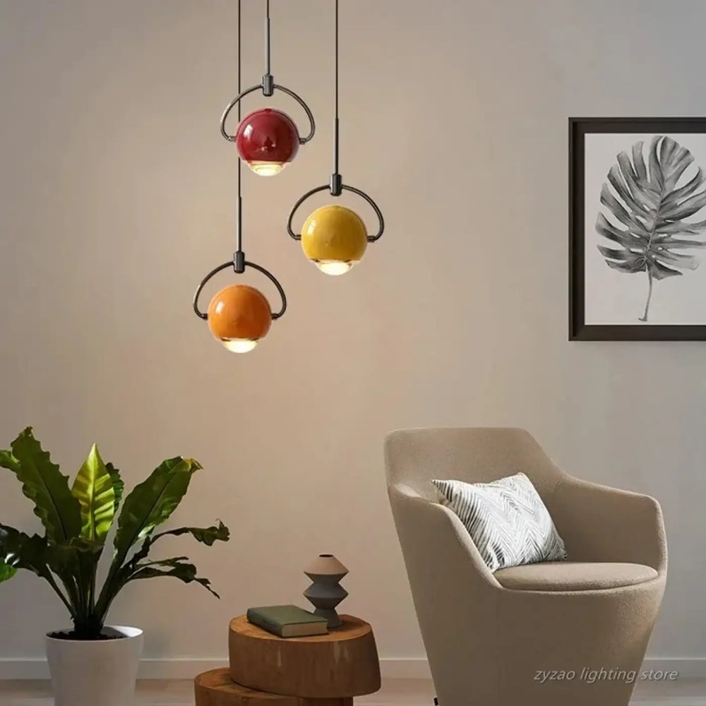 Suspension luminaire orion avec boules en céramique rouge jaune orange et anneaux métalliques noirs suspendus