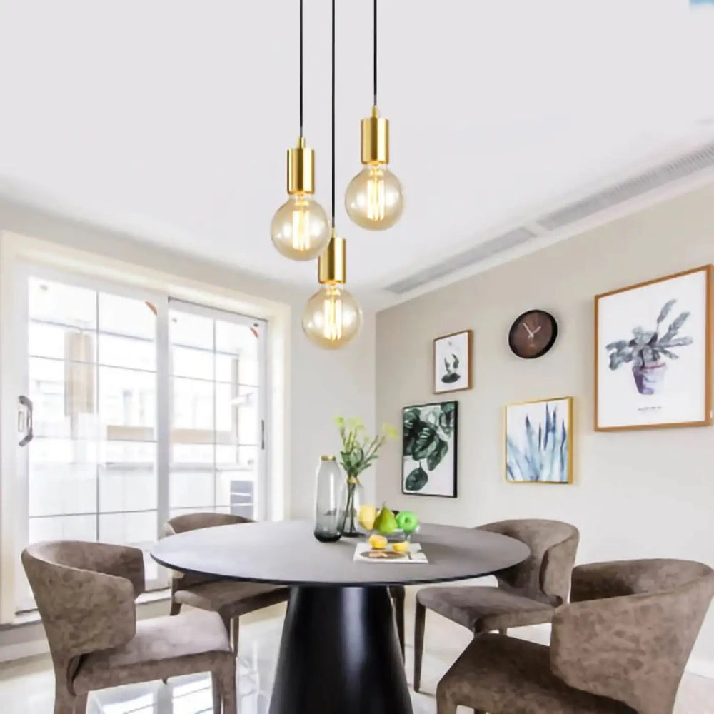 Suspension luminaire uranus en finition or avec ampoules à filament apparent suspendues au-dessus d’une table à manger