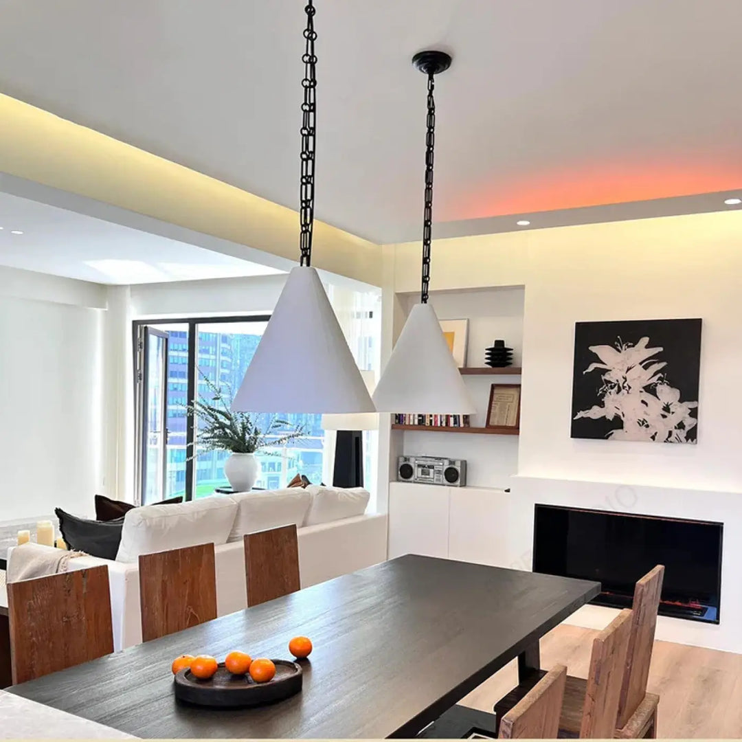 Deux suspension luminaire conique blanches modernes suspendues par des chaînes noires au-dessus d’une table en bois foncé