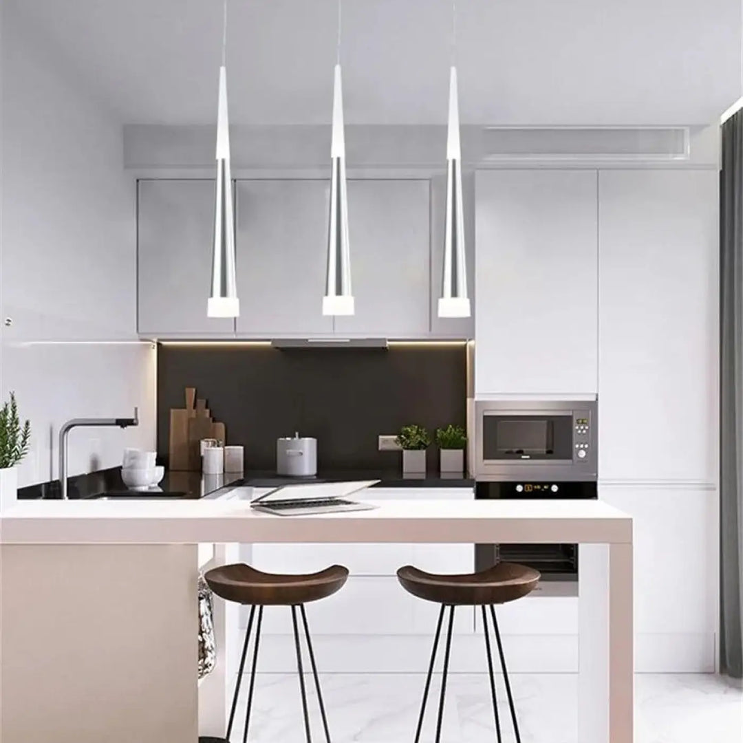 Trois suspension luminaires dartel en finition métallique avec un design effilé suspendus au-dessus de lîlot de cuisine