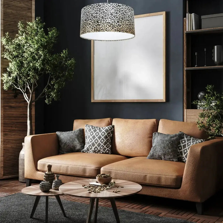 Suspension luminaire safari en léopard crème avec canapé en cuir tan et coussins à motifs gris et blanc design léopard