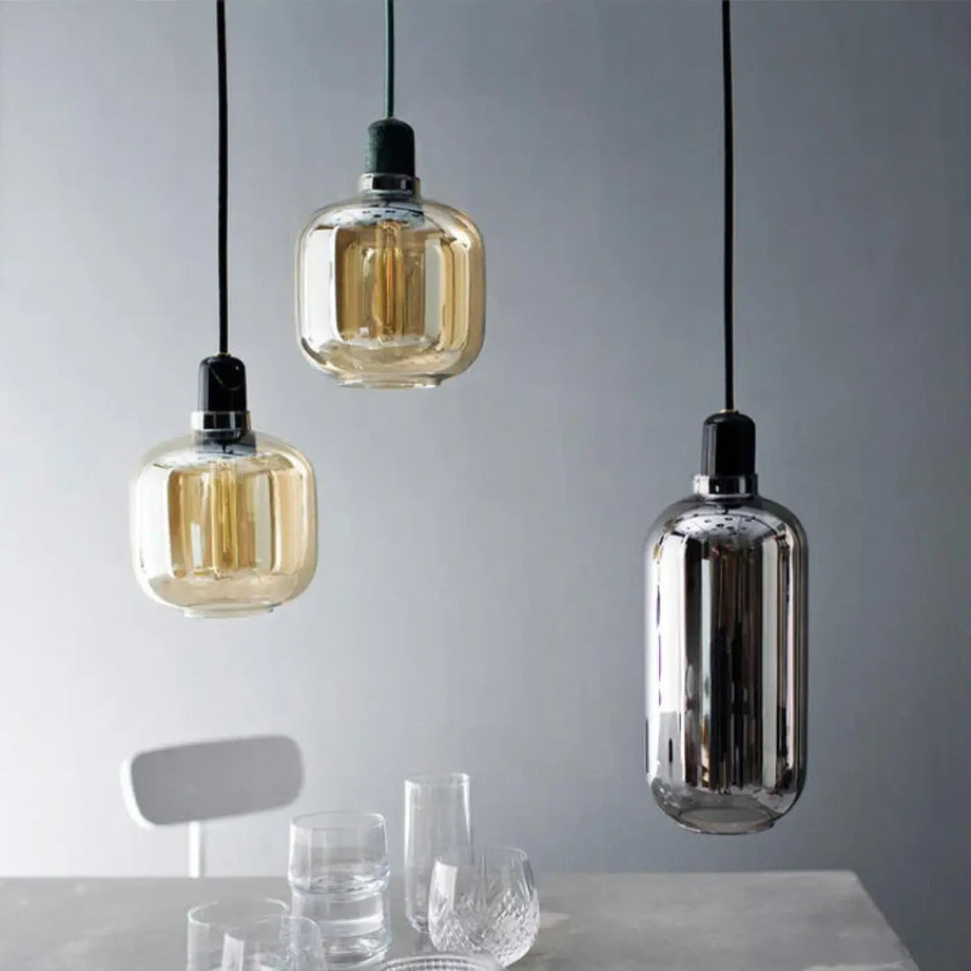 Suspension luminaire hyalis avec trois formes arrondies en verre teinté ambre et chrome suspendues par cordons noirs