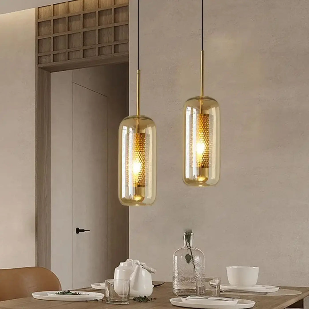 Suspension luminaire eloria avec deux pendentifs dorés et verre transparent aux nuances ambrées en motif nid dabeille